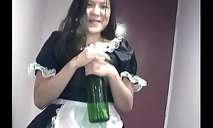 Young Asian unladylike dressed as A a maid indulges herself with a bottle for effervescent on camera for u